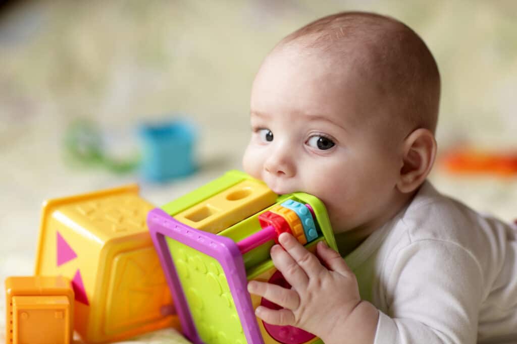 a baby chewing on a plastic toy