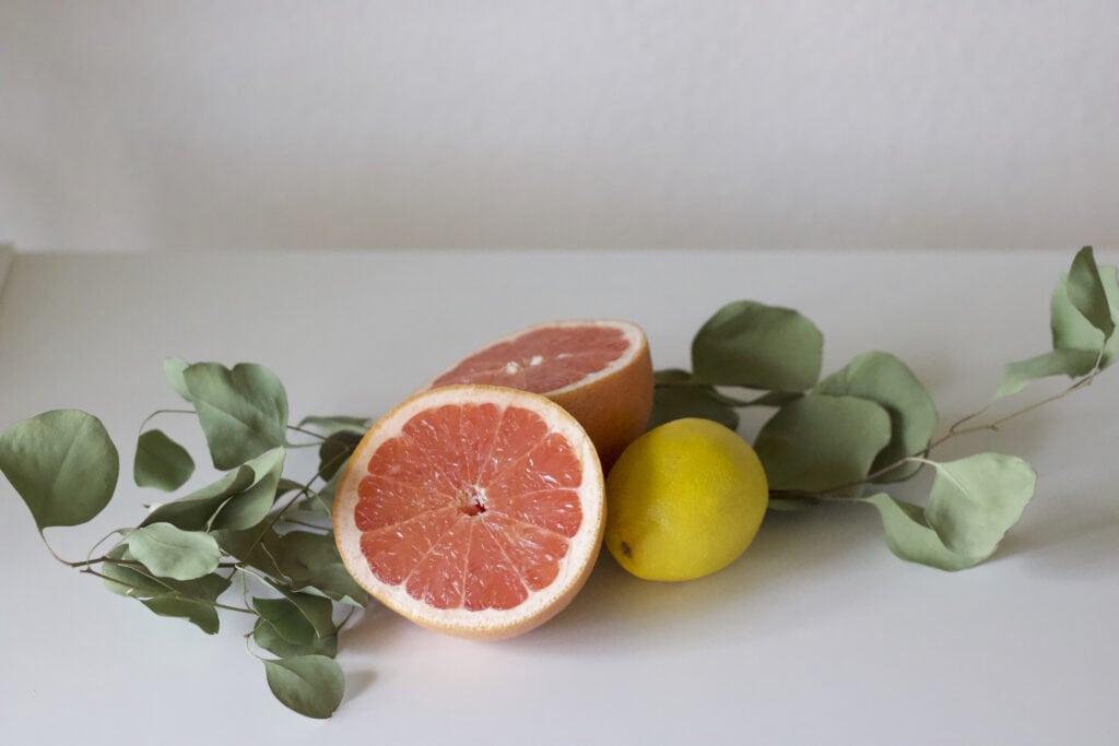 a grapefruit next to a lemon and some leaves