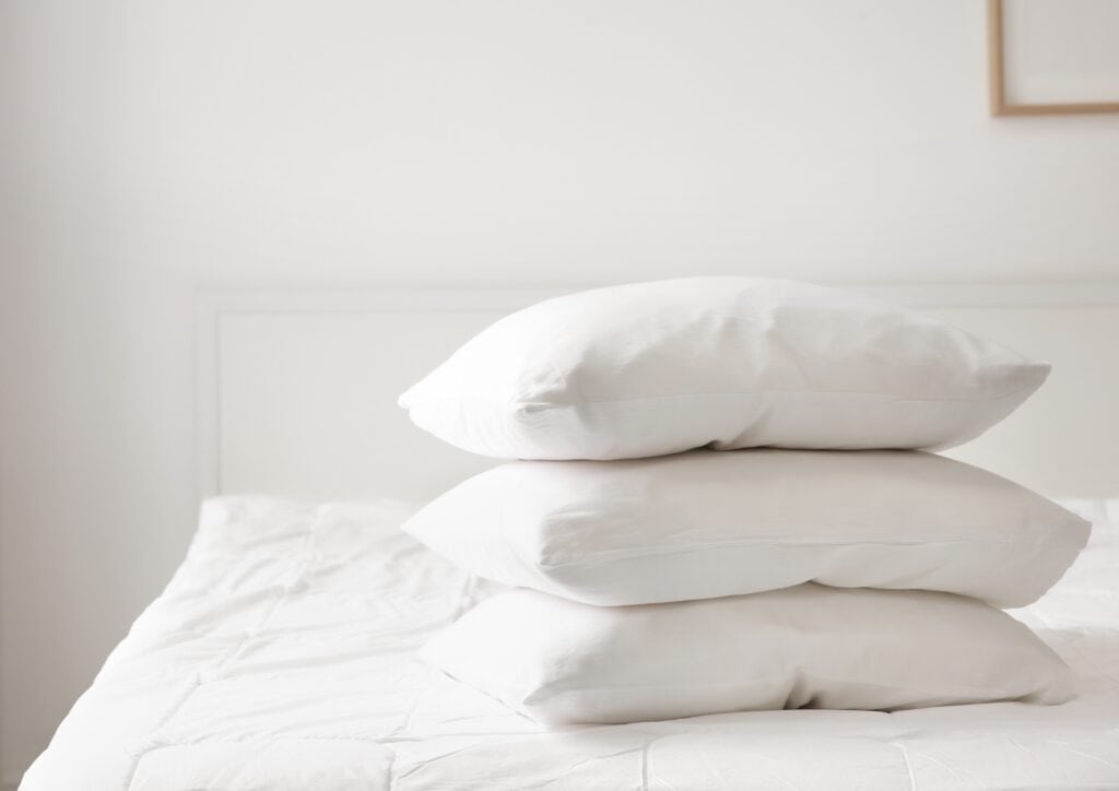 3 polyester pillows sitting on a bed