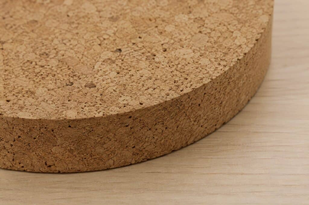 Close-up of a natural cork furniture material surface showing its textured, renewable composition on a light wood background.