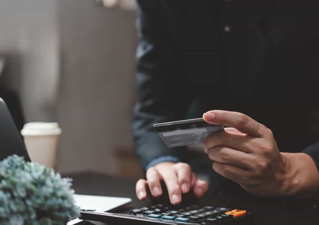person sitting at a computer with their credit card buying an item online 