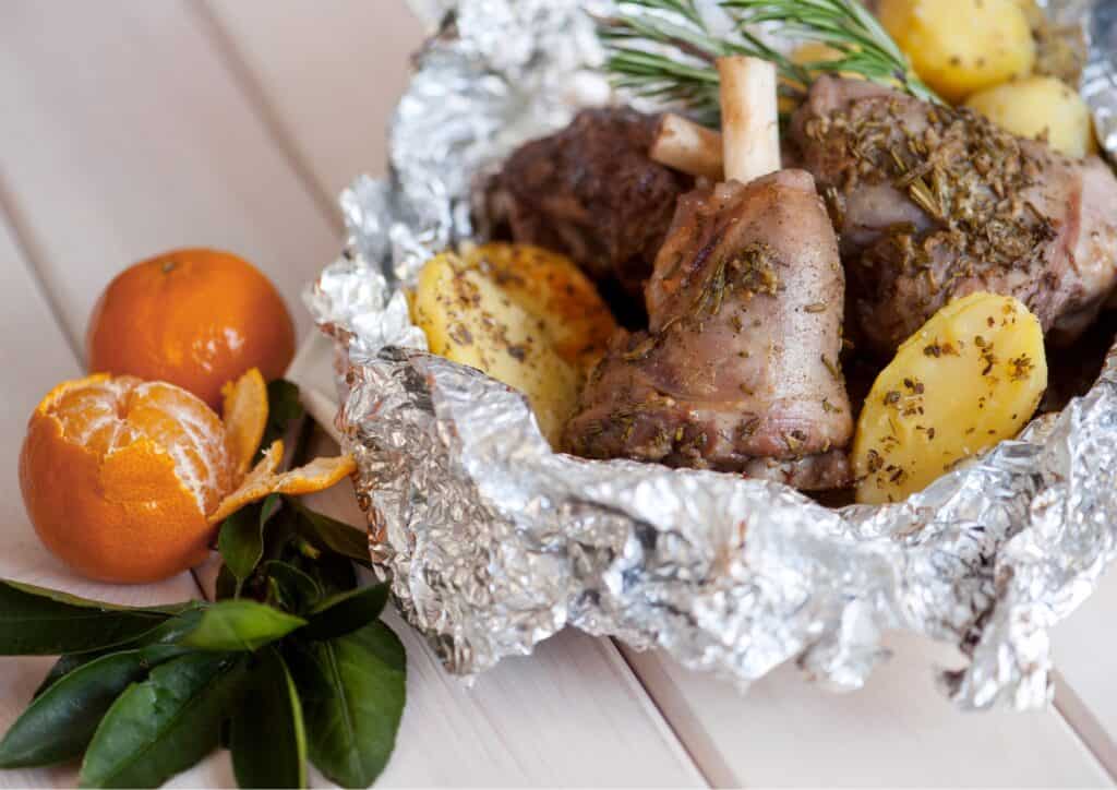 chicken and potatoes in a bowl wrapped in aluminum foil