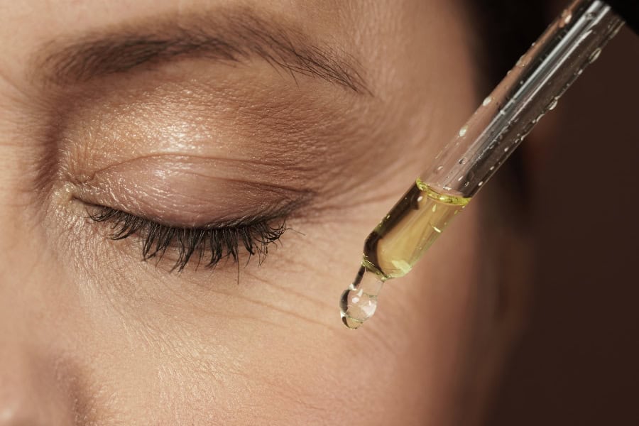 a woman applying castor oil to her wrinkles around her eye