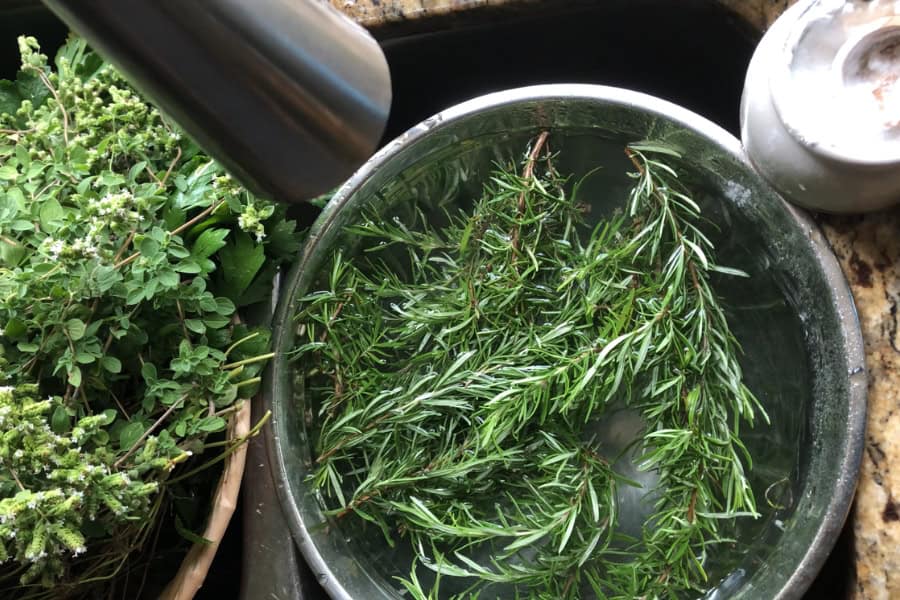 Herbs being washed in the sink using baking soda and water mixture