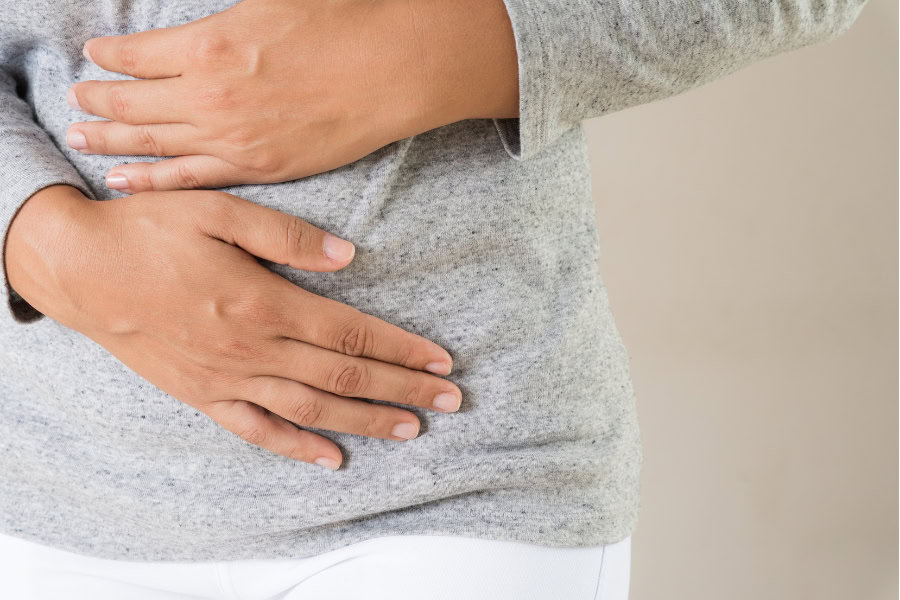 a woman holding her stomach from bloating pain