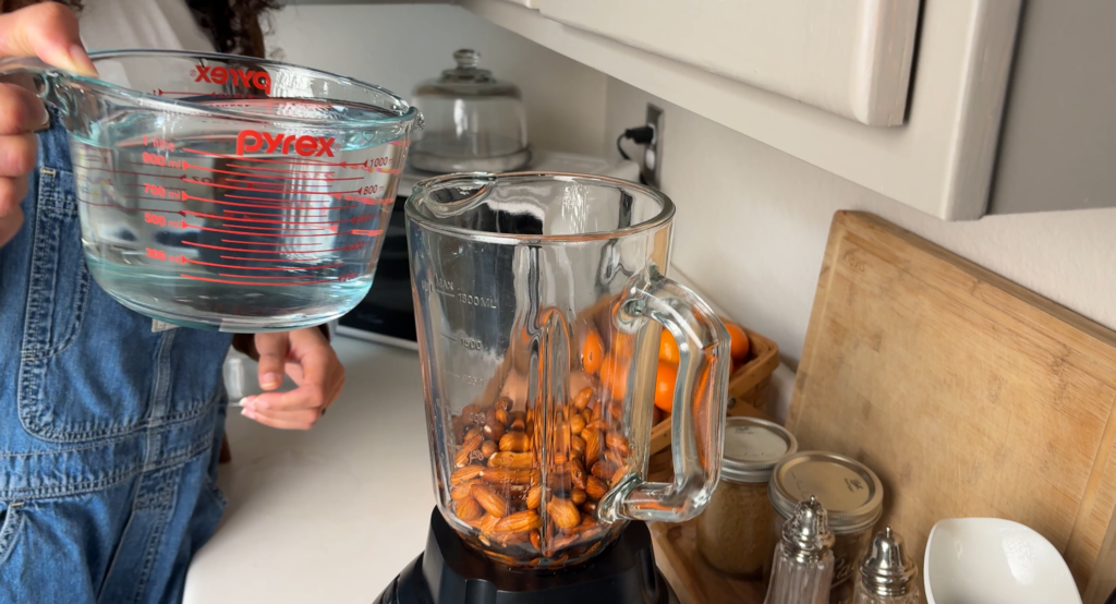 pouring water into almonds in blender