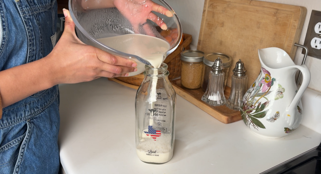 pouring almond milk into repurposed milk bottle