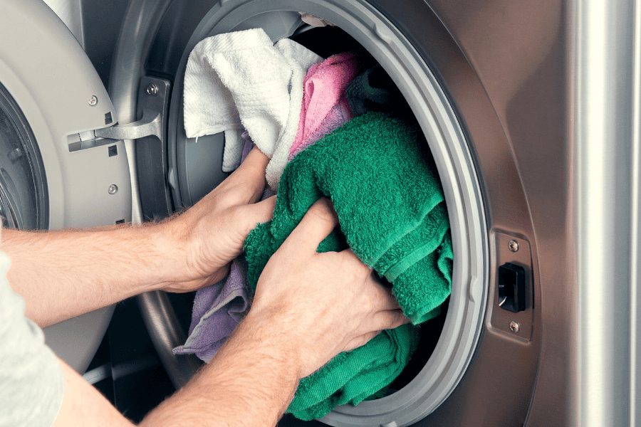 putting clothes into a washer