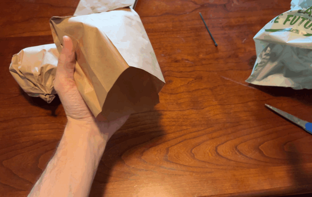 stuffing a brown paper bag with a grocery bag
