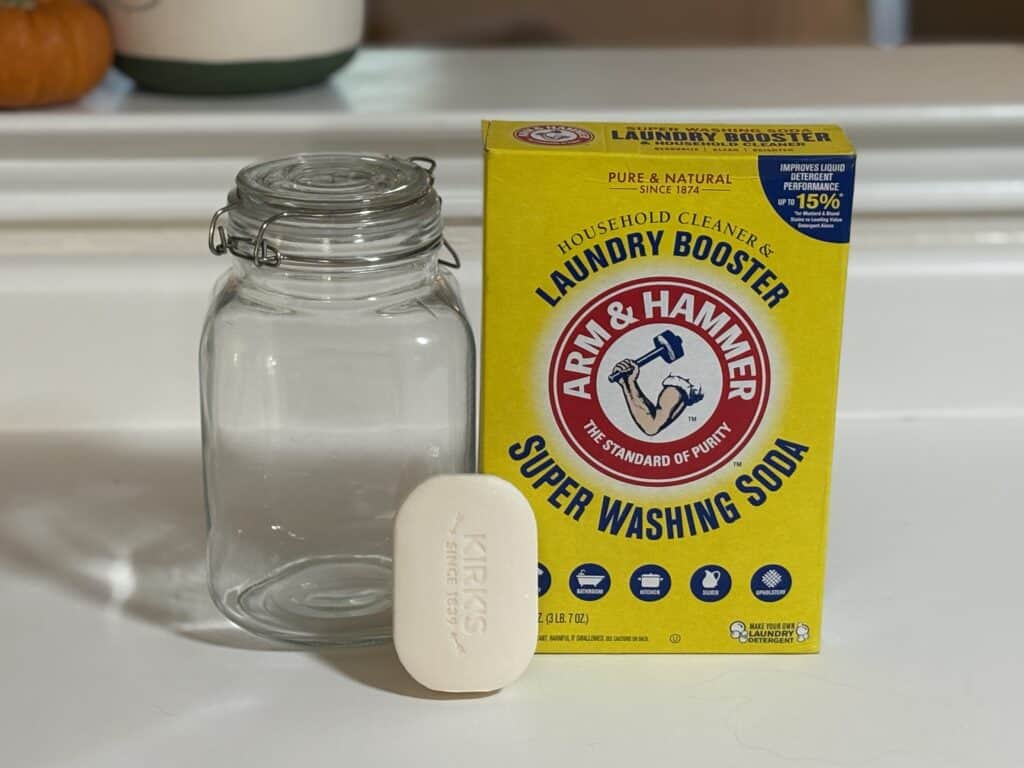 a glass jar next to a bar of castile soap and a box of washing soda