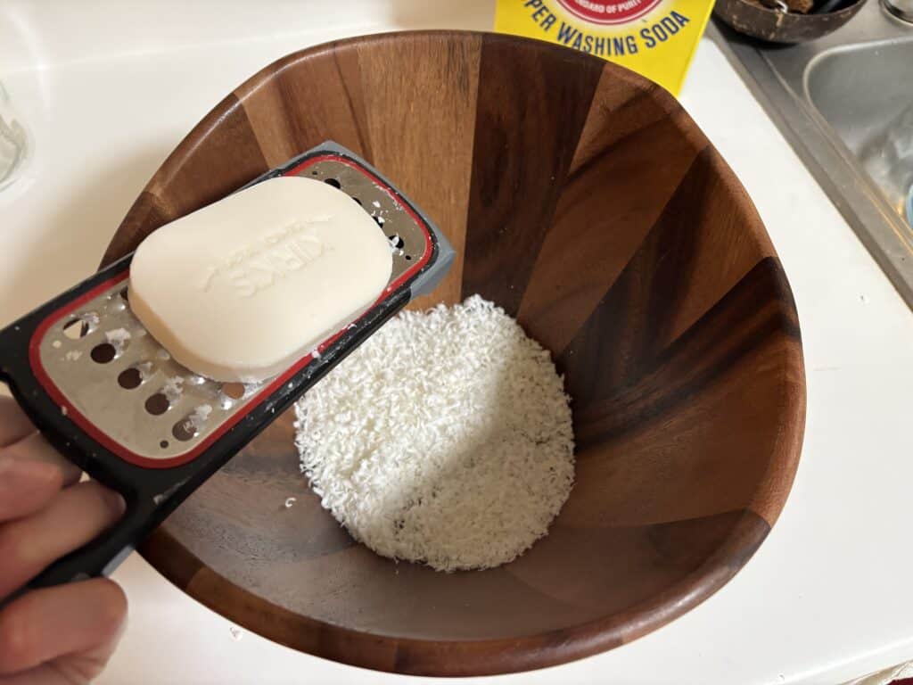 grating a bar of castile soap into a bowl
