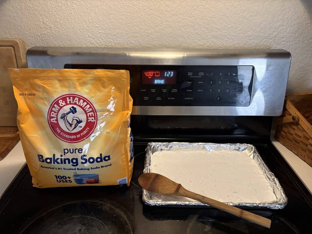 an oven set to 400 with a sheet of baking soda, a bag of baking soda, and a wooden spoon