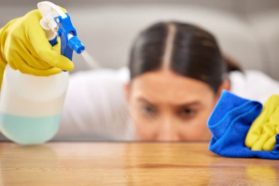 a woman spraying a cleaner on a counter