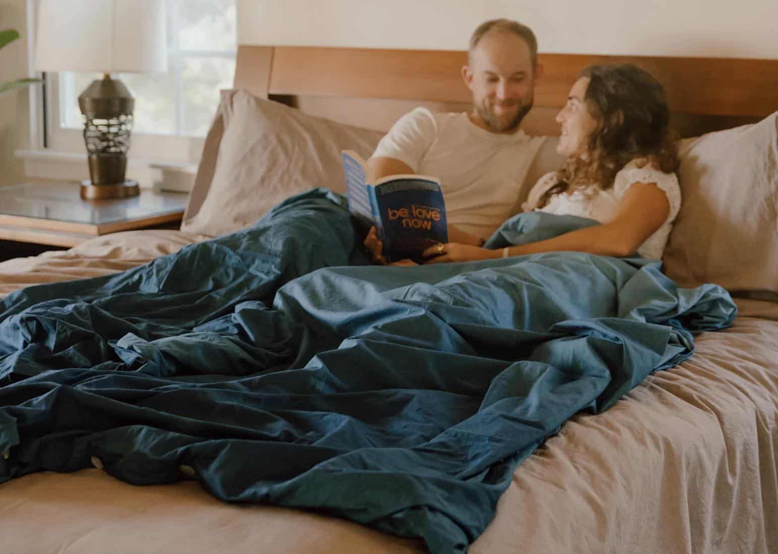 a couple laying on a bed with a weighted blanket