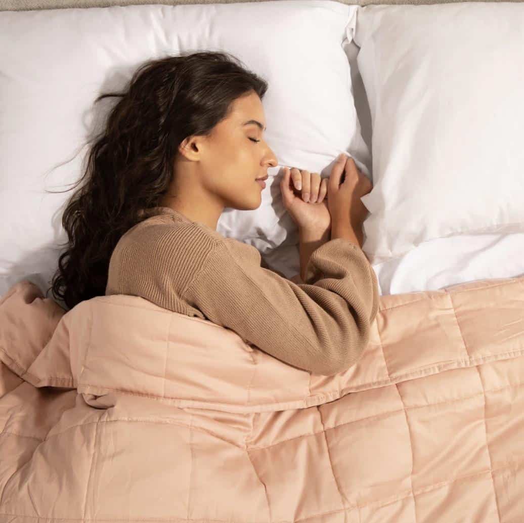 a woman sleeping under a weighted blanket