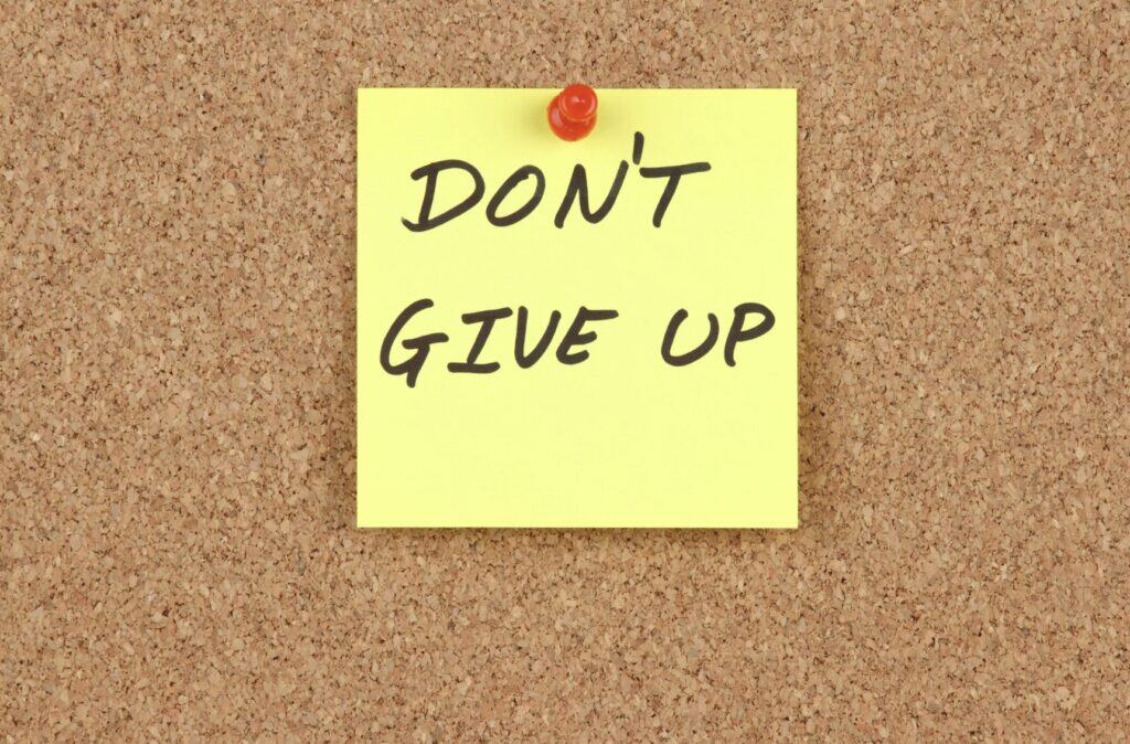 a post it note that reads "do not give up"