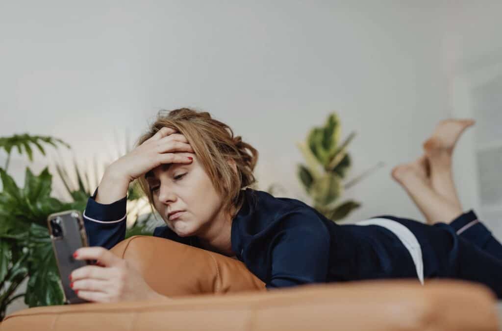 a woman looking stressed while scrolling on her phone