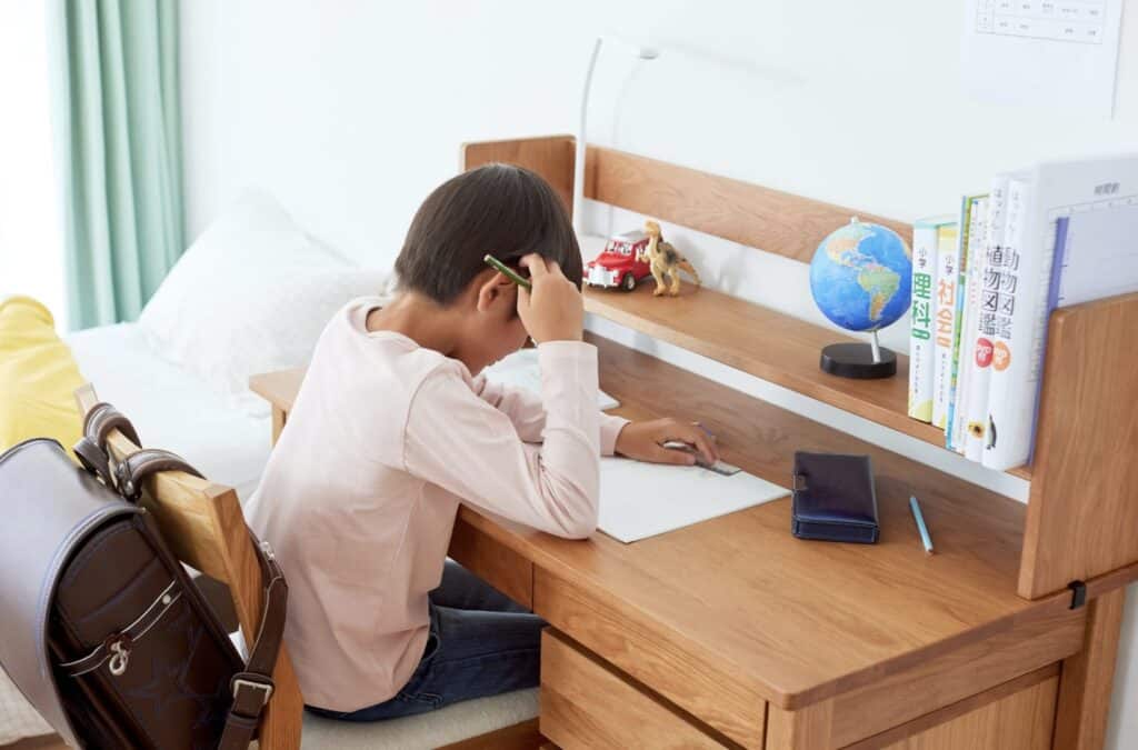 a child studying at a wooden desk in a small room