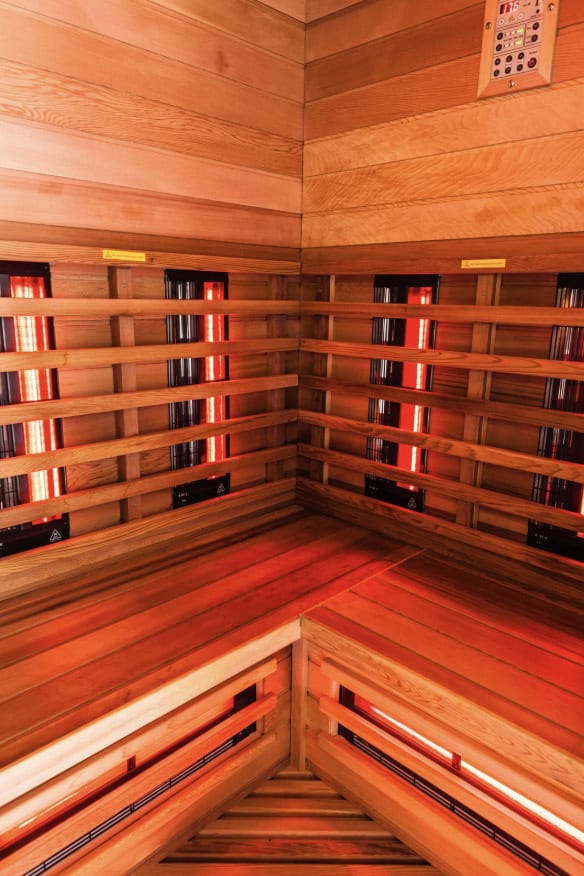 Infrared sauna interior with wooden benches and wall-mounted heating panels glowing red