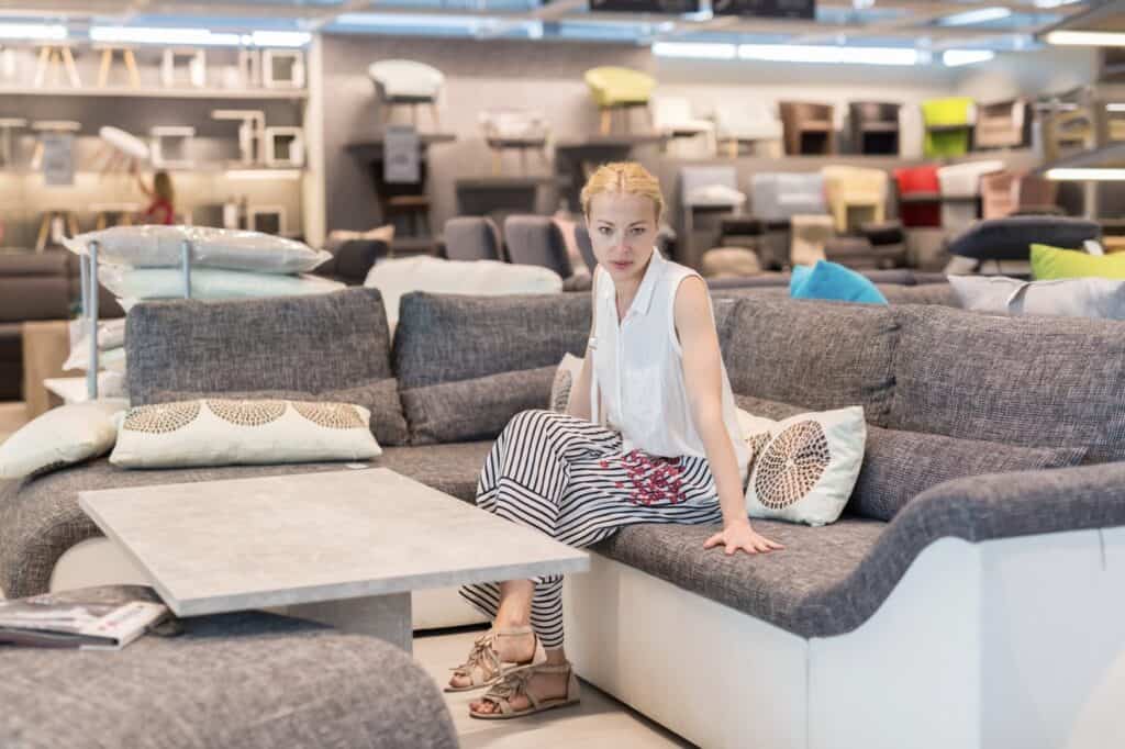 Woman testing a sectional sofa in a furniture store showroom