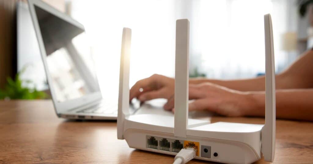 WiFi router on a desk near a laptop in a home workspace