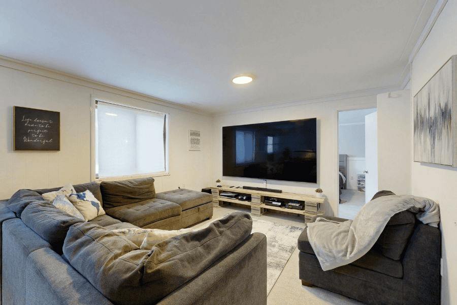 Modern living room with sectional couch, wall-mounted TV, neutral decor, and soft lighting