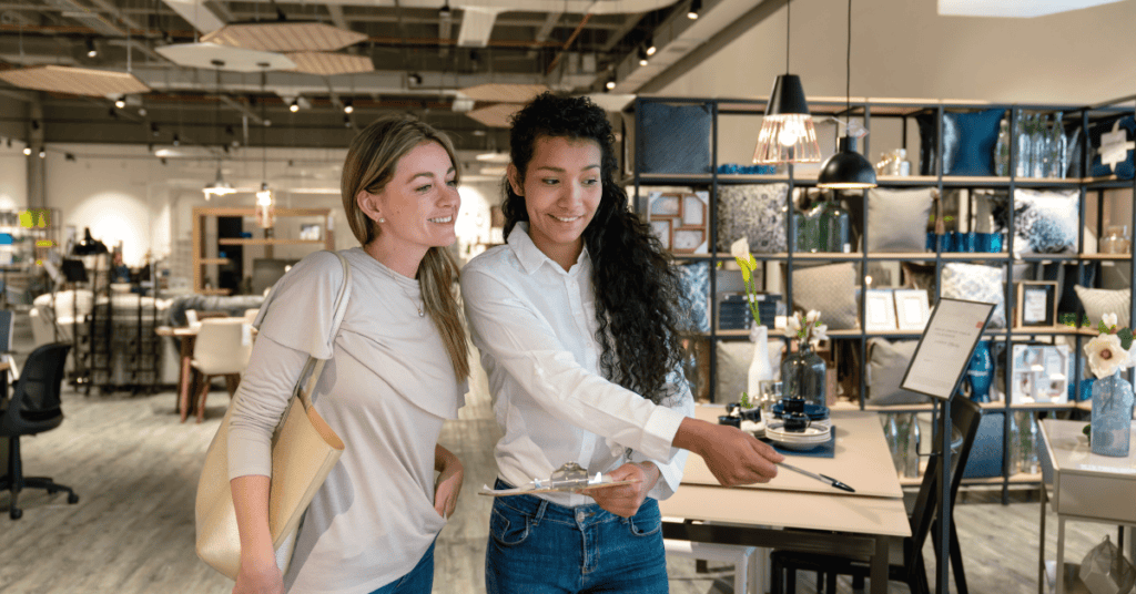 Shopper reviewing furniture details with a store employee in a furniture showroom.