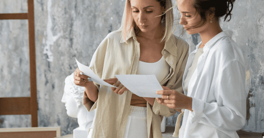 Two shoppers reviewing furniture product details on paper while comparing options.