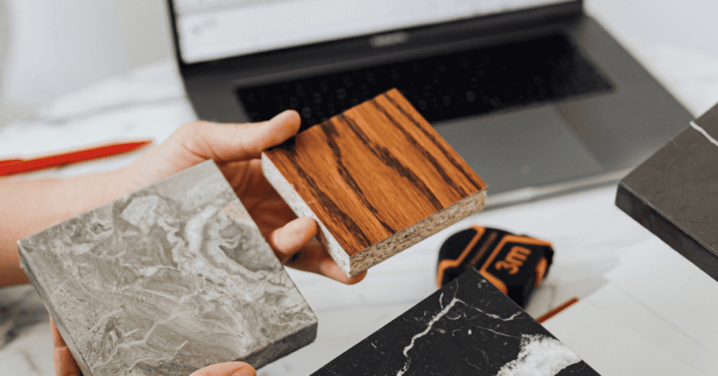 Person comparing wood, stone, and surface material samples for furniture selection.