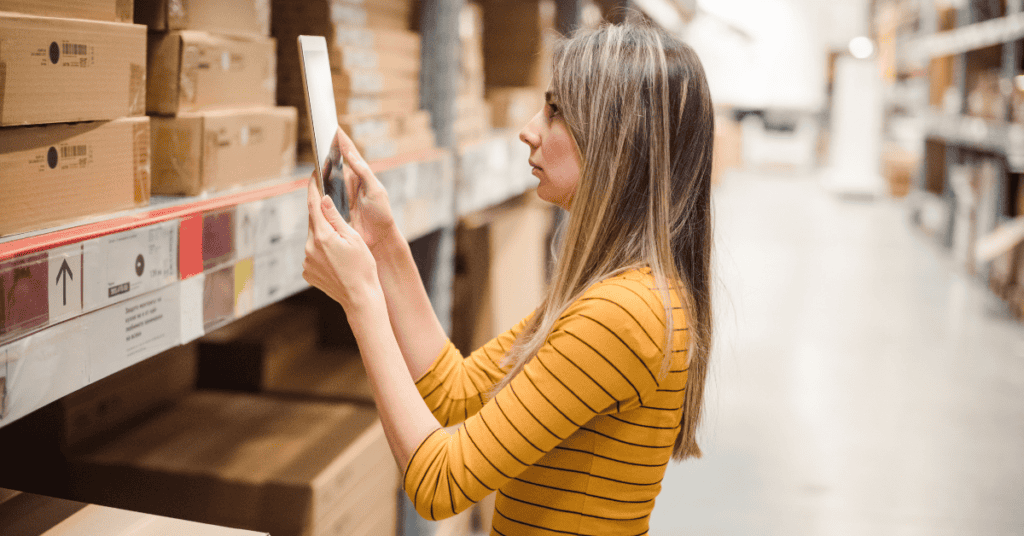 Shopper reviewing a furniture shopping checklist on a tablet in a warehouse aisle.