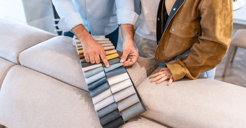 People comparing couch fabric swatches on a beige sofa