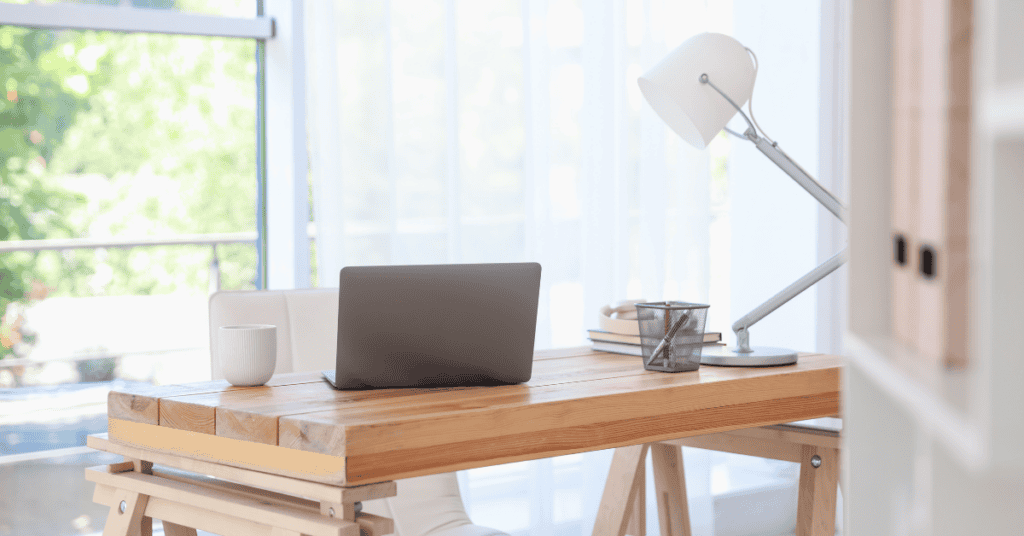 Bright home office with a wooden desk, laptop, and open window for fresh airflow.