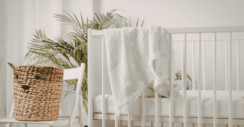 Bright nursery with a white crib, natural basket, plant, and soft neutral textiles.