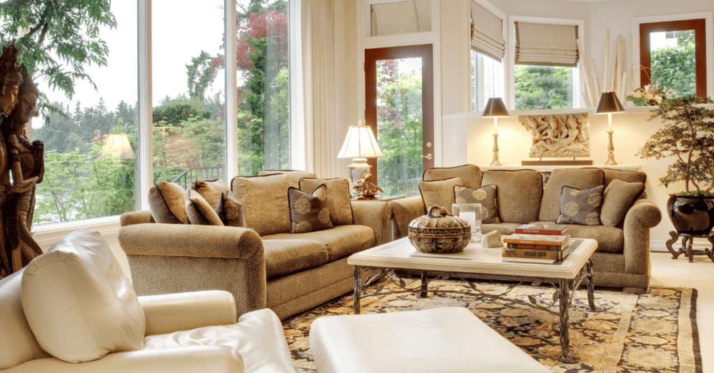 Bright living room with upholstered couches near large open windows.