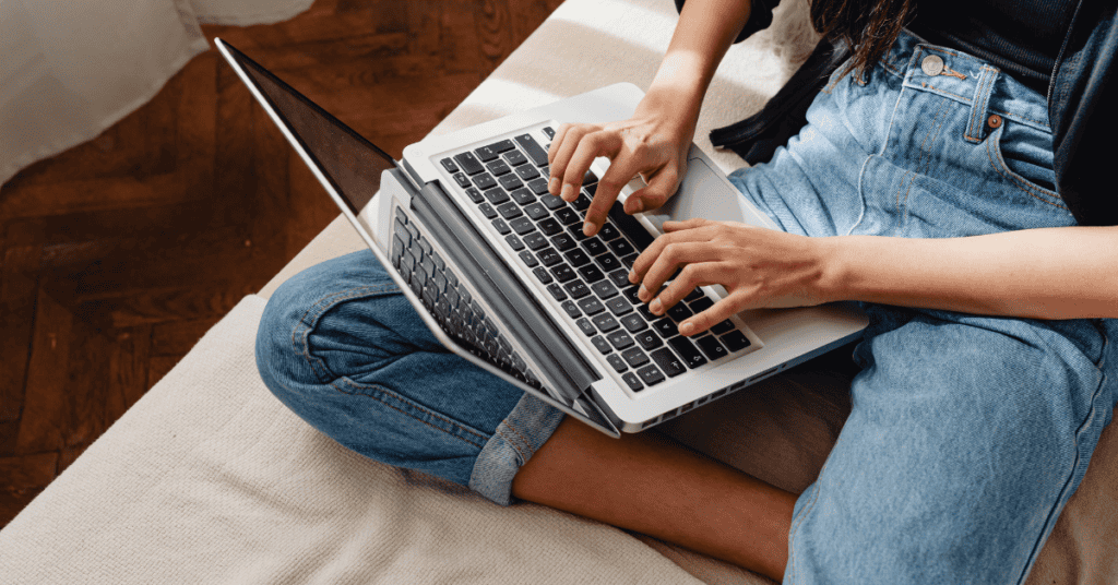 person sitting on bed while researching mattress materials on a laptop