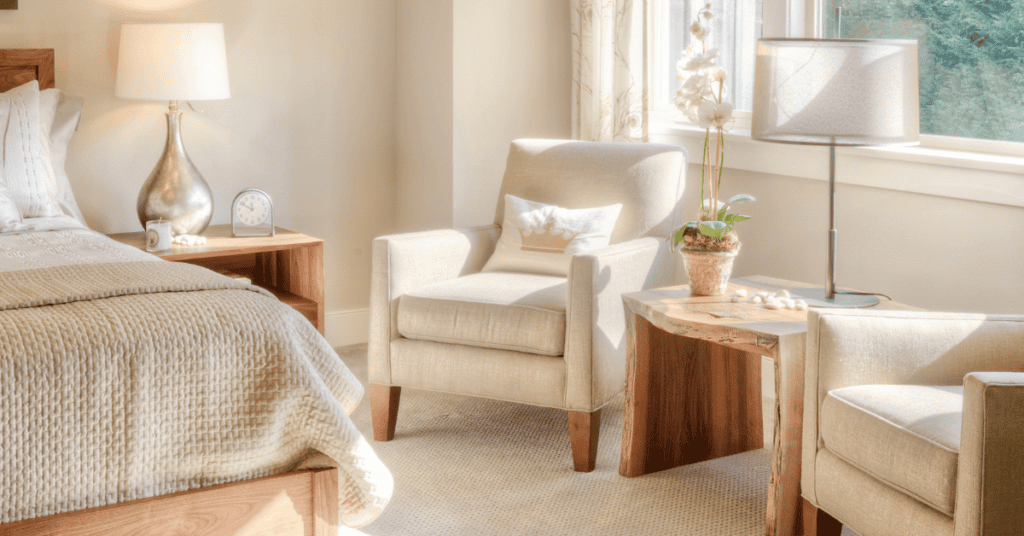 Sunny bedroom sitting area with upholstered chairs, wooden furniture, and an open window.