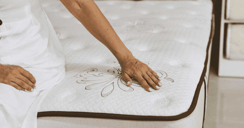 person pressing hand on a mattress to test its comfort and surface feel