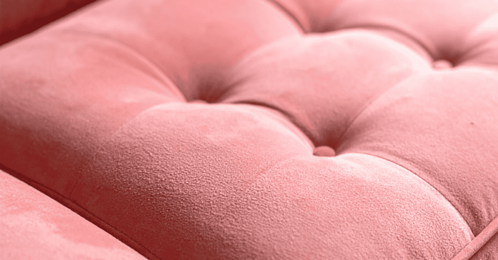 Close-up of a pink upholstered foam cushion with soft tufted fabric.