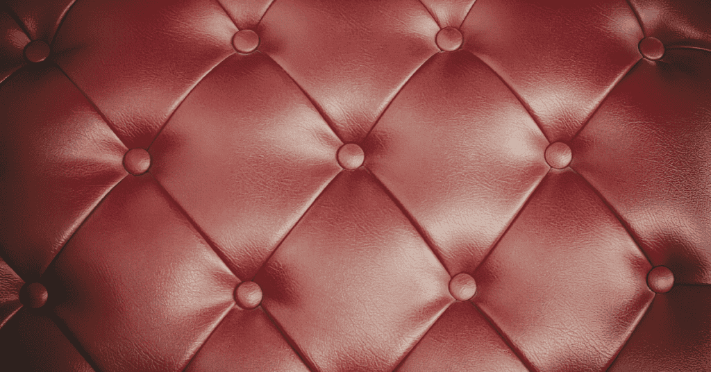 Close-up of red vinyl upholstery with a tufted leather-like texture.