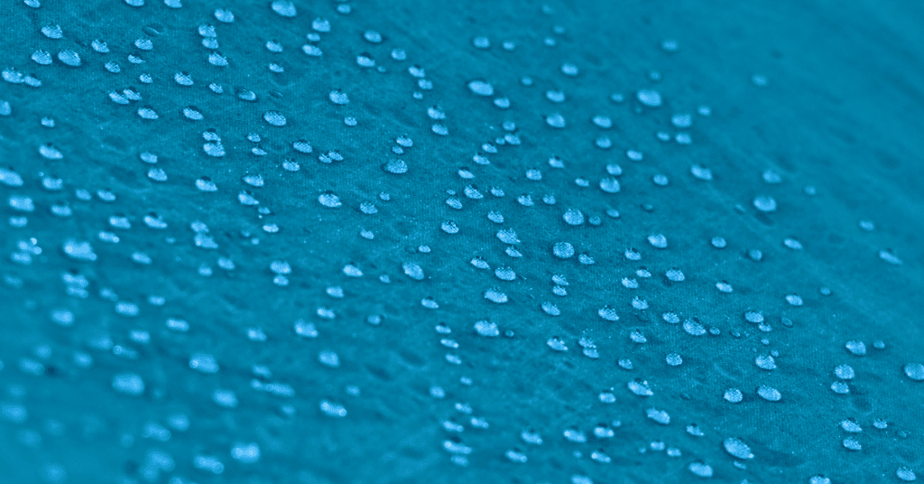 Water droplets beading on blue water-repellent upholstery fabric.