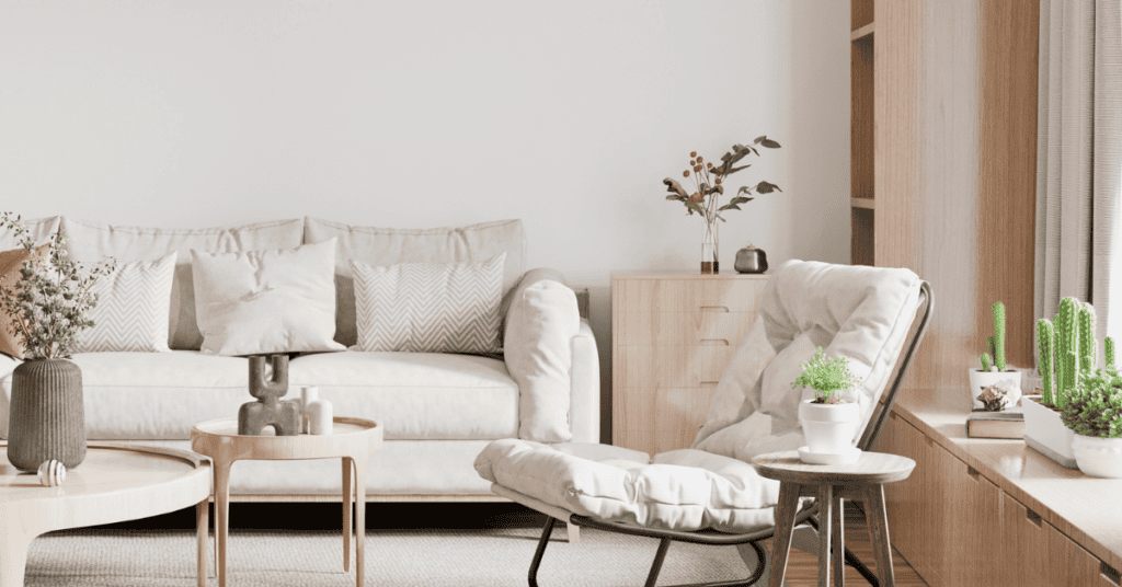 Bright neutral living room with a cream sofa, natural wood furniture, plants, and soft decor.