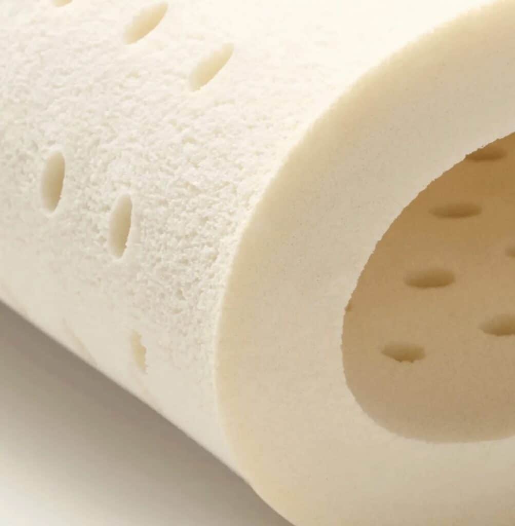 Close-up of a rolled natural latex foam insert with ventilation holes, illustrating a common natural filling used in some acupressure mats.