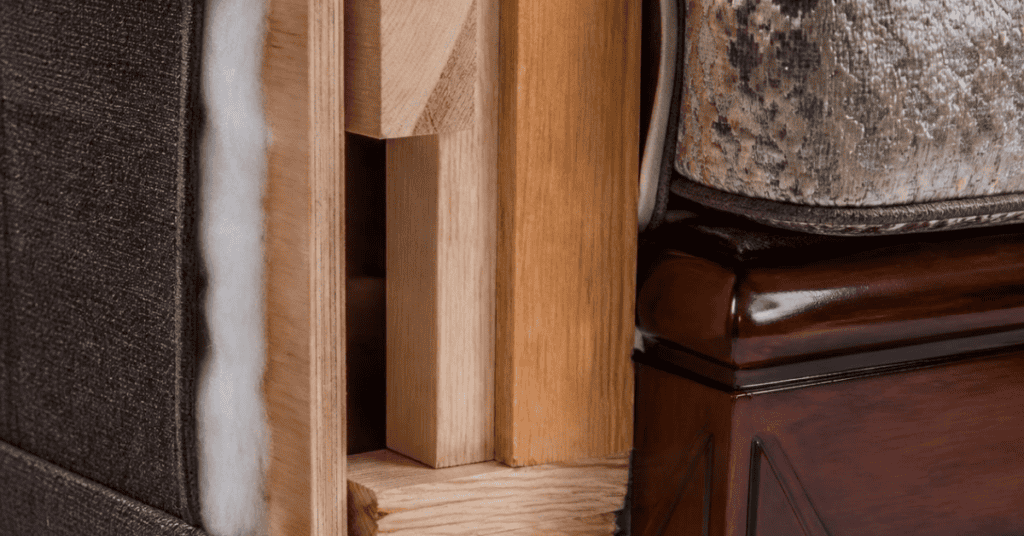 Close-up of upholstered furniture showing fabric, foam padding, a wooden frame, and finished wood.