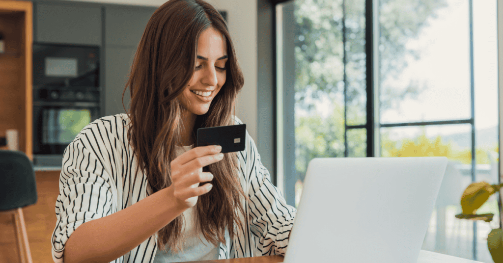 Woman shopping online with a laptop and credit card, suggesting mattress research or online mattress purchasing.