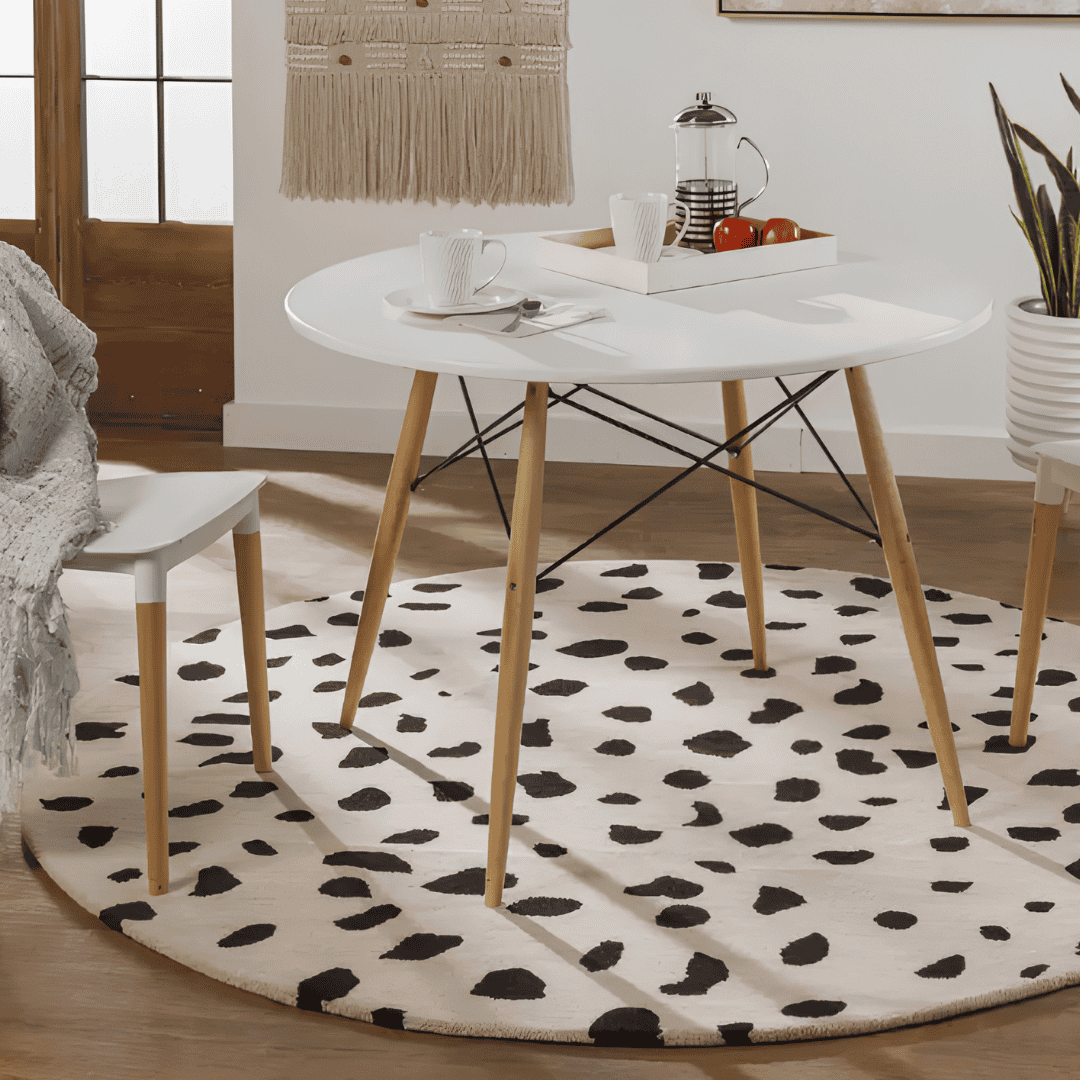 Black-and-white spotted round rug beneath a dining table in a bright room.