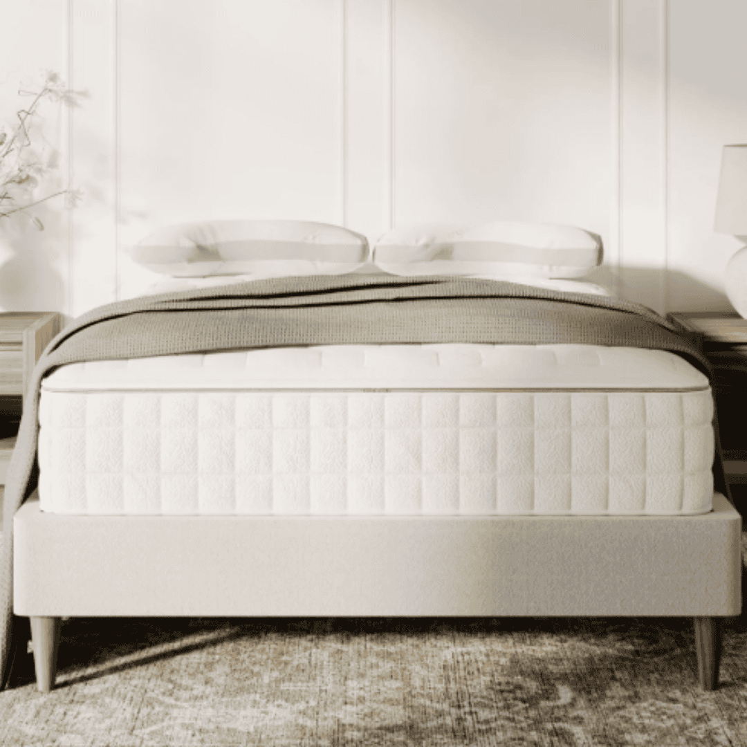 Neutral upholstered bed with a white mattress, soft green blanket, and matching bedside furniture.