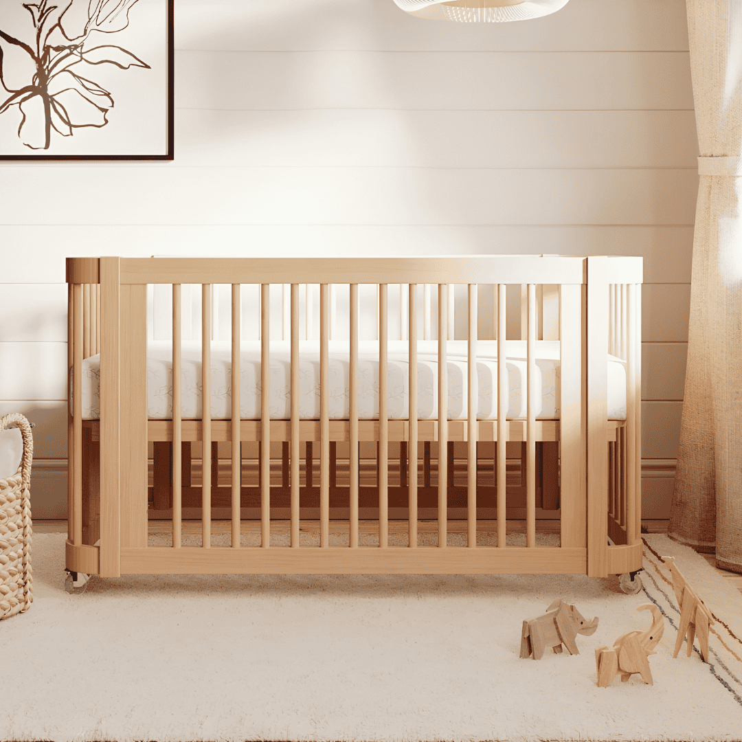 Natural wood Nestig crib on wheels in a softly lit nursery.