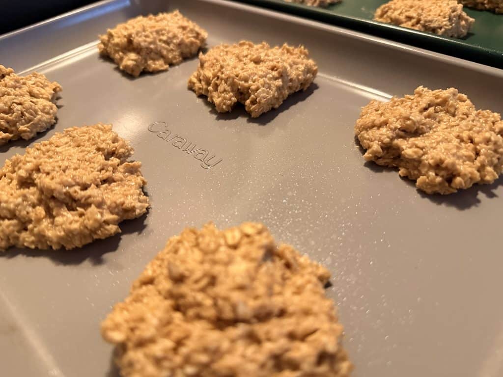 Oat-flour cookie dough portions placed directly on a gray Caraway baking sheet without parchment.