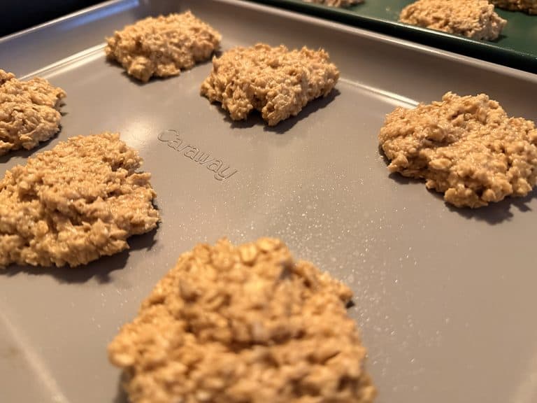Oat-flour cookie dough portions placed directly on a gray Caraway baking sheet without parchment.