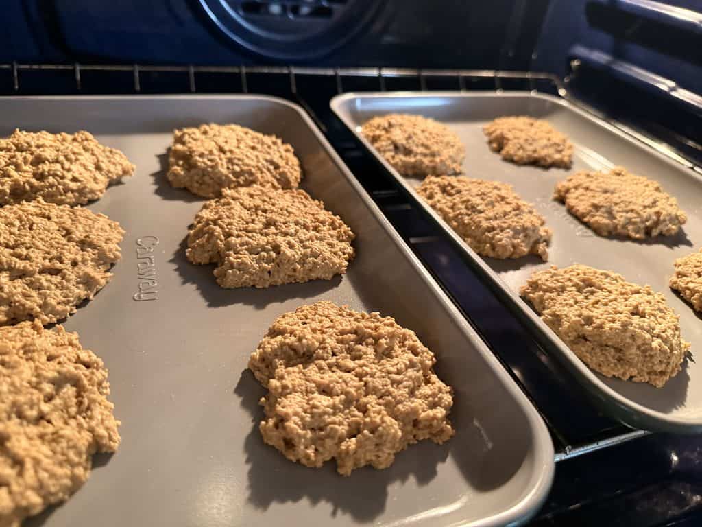 Two Caraway baking sheets holding oat-flour cookies side by side on an oven rack
